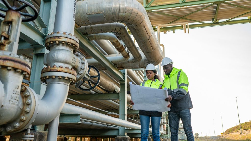 Engineer holding blueprint drawing to checking gas pipeline.